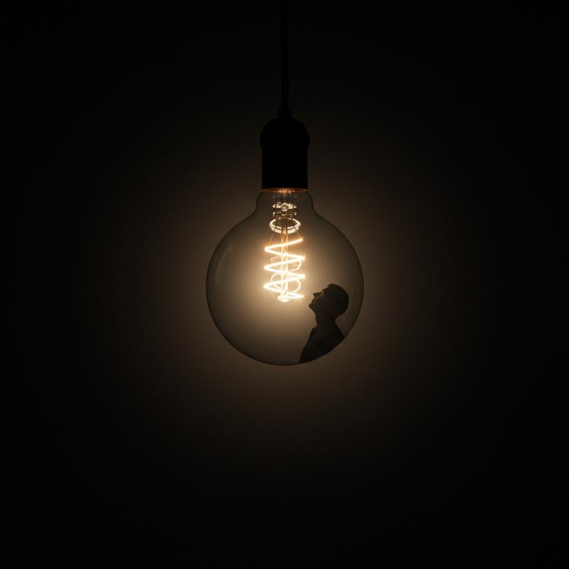 A single illuminated lightbulb in darkness, representing genuine leadership inspiration